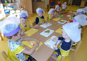 05 Dzieci ubrane w strój kucharza kroją na deskach owoce